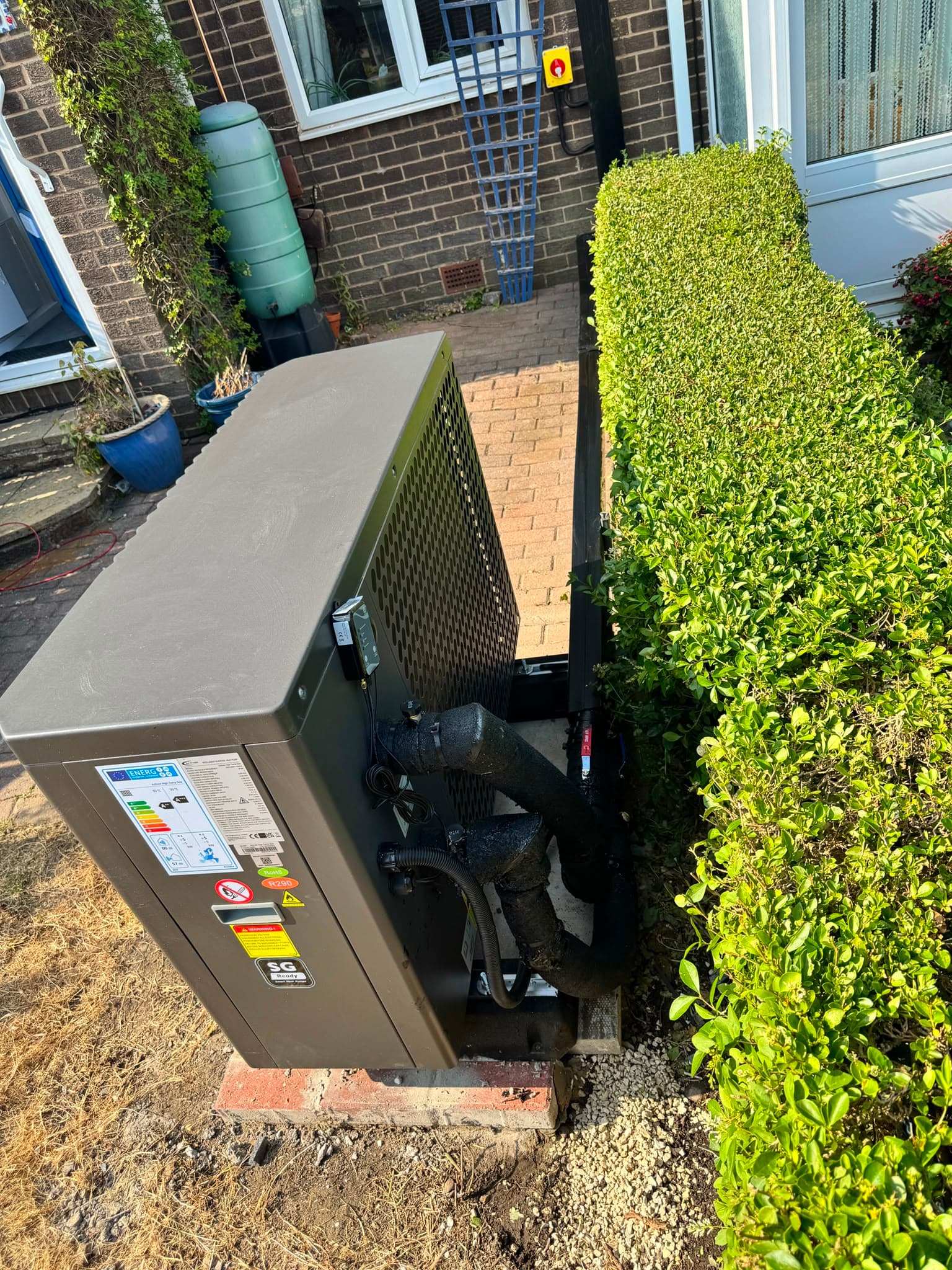 ActivAir air source heat pump positioned alongside the hedge at the front of the property