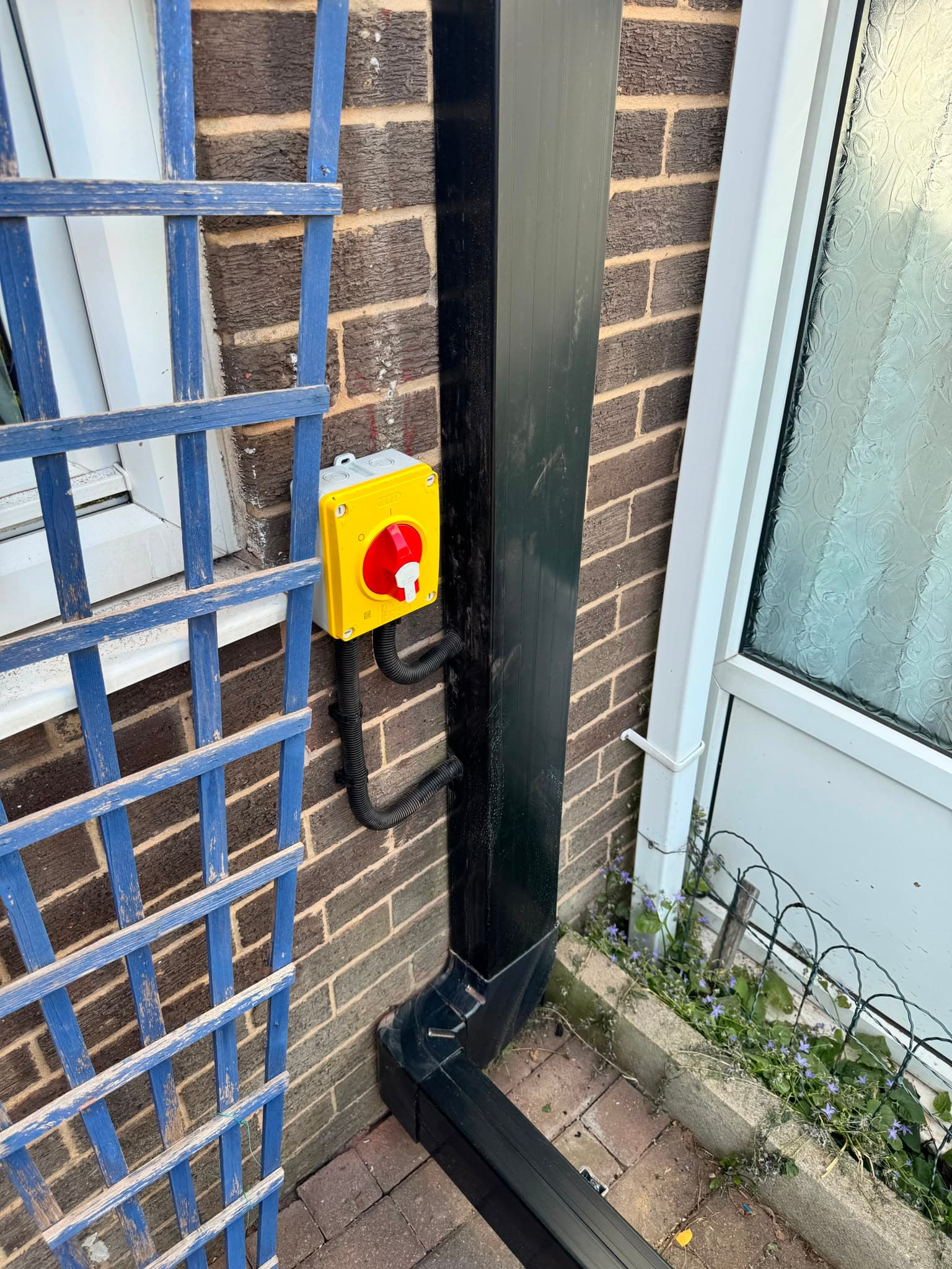 External rotary isolator switch and neat black trunking carrying the heat pump services down the wall