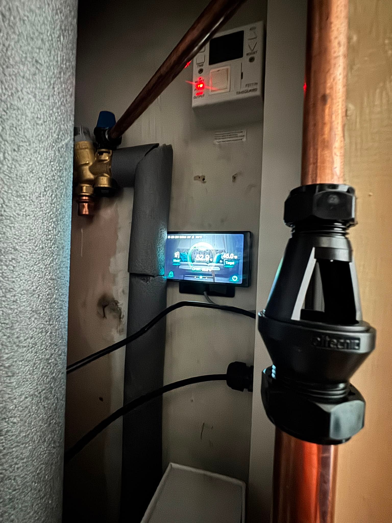 Heat pump controller display mounted in the airing cupboard with lagged pipework alongside
