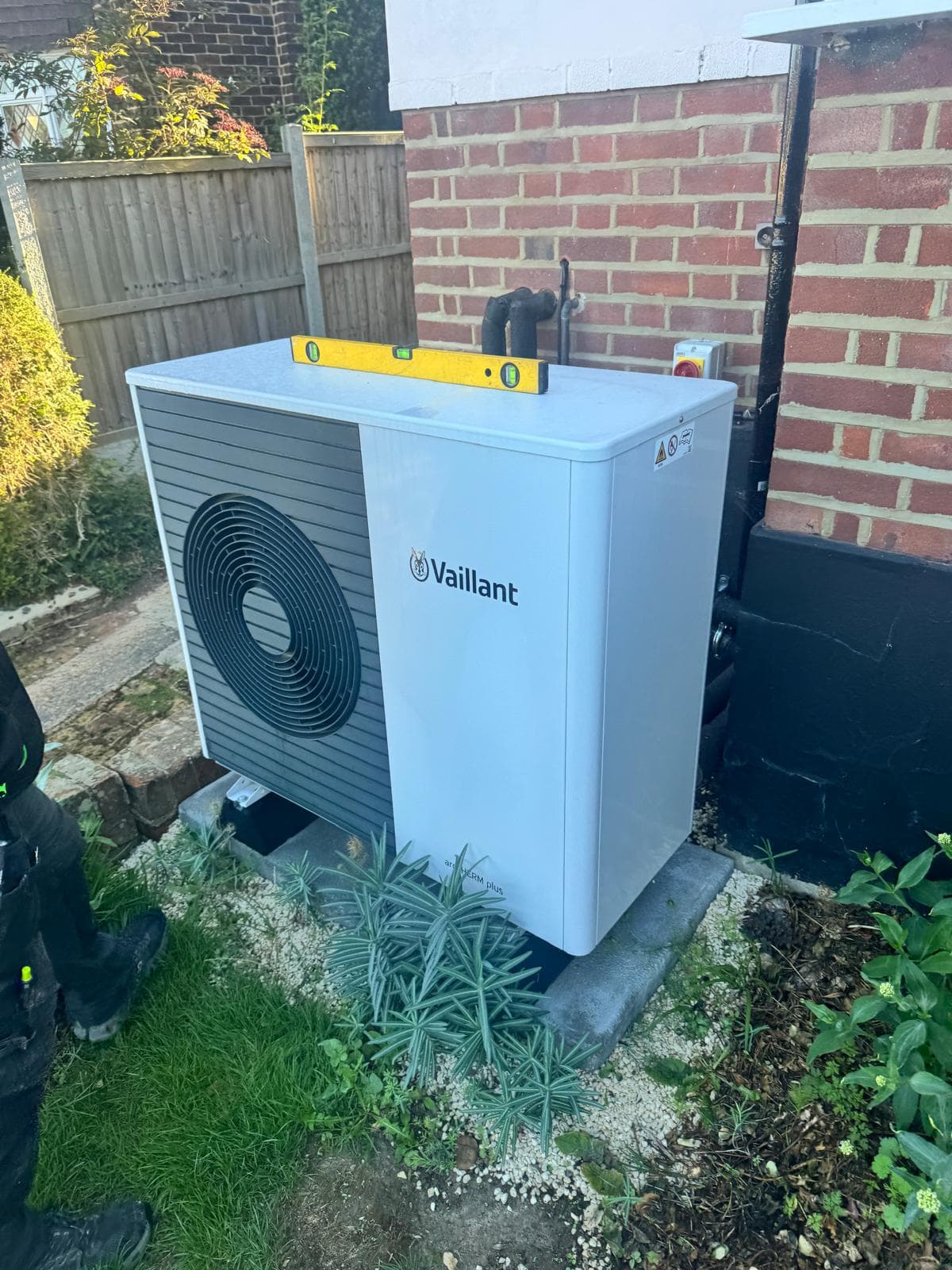 Vaillant aroTHERM plus air source heat pump installed outside against a brick wall, levelled with a spirit level on top