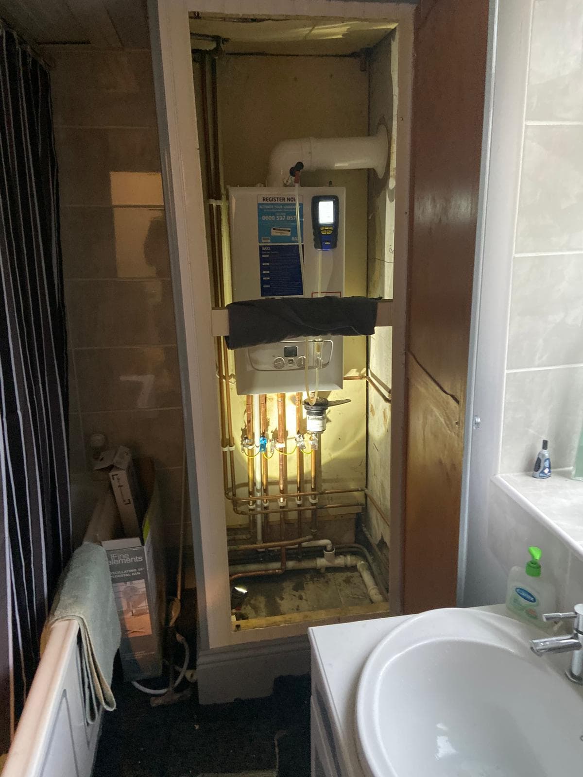 New Baxi combi boiler in an airing cupboard being commissioned with a flue gas analyser
