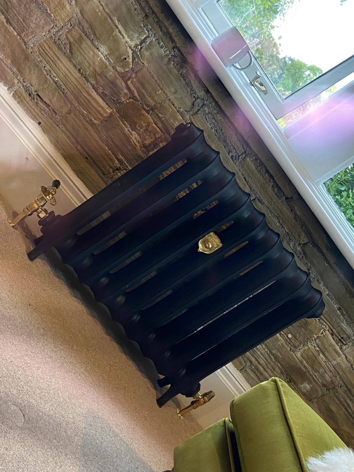 Cast iron radiator with brass period valves in a stone-walled living room