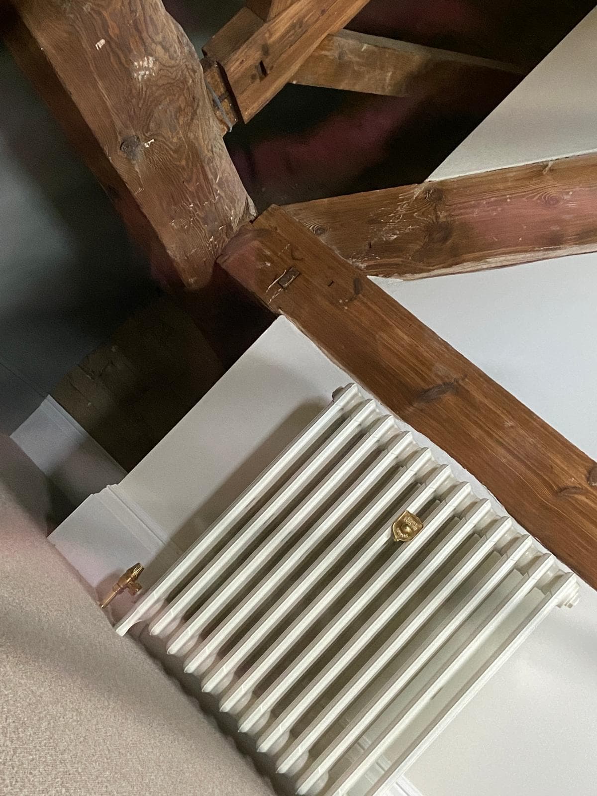 White column radiator beneath exposed timber roof beams