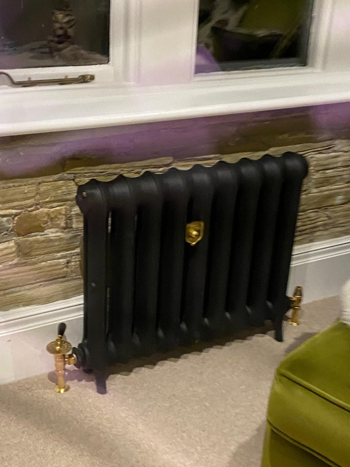 Cast iron radiator against exposed stone beneath a cottage window