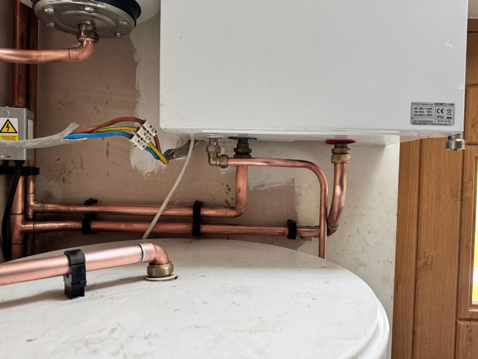 Neat copper flow and return connections beneath the relocated electric boiler