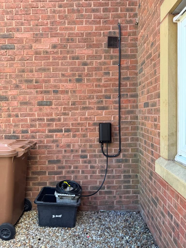 Weatherproof outdoor EV charging connection with neatly clipped cable run down the house wall