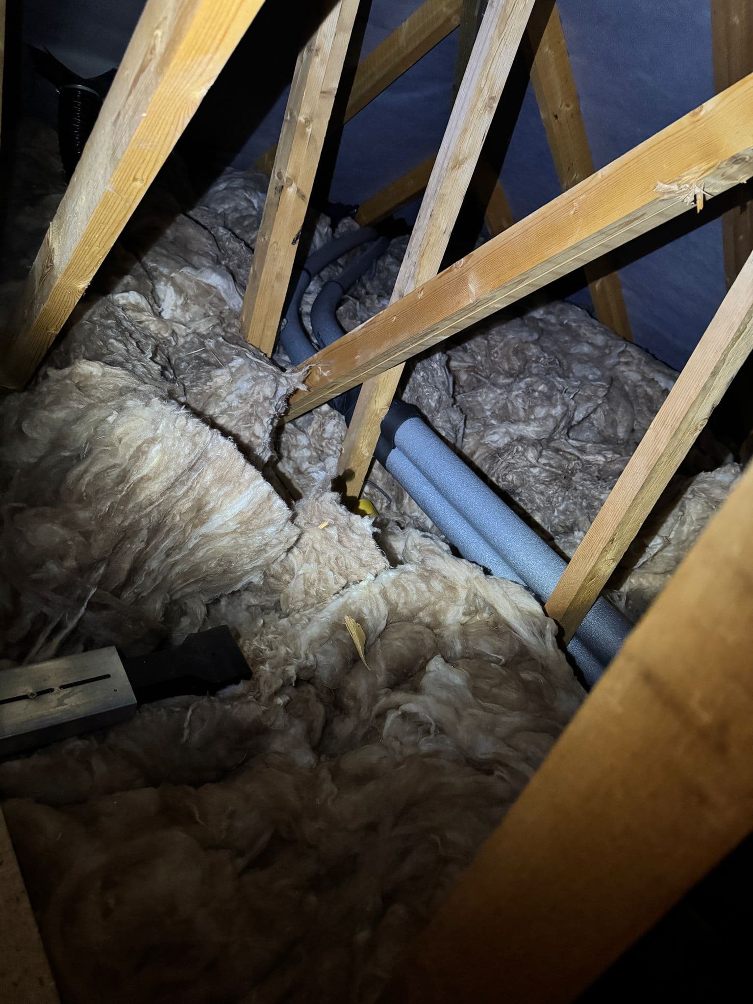 Insulated pipework routed neatly through loft insulation between the rafters
