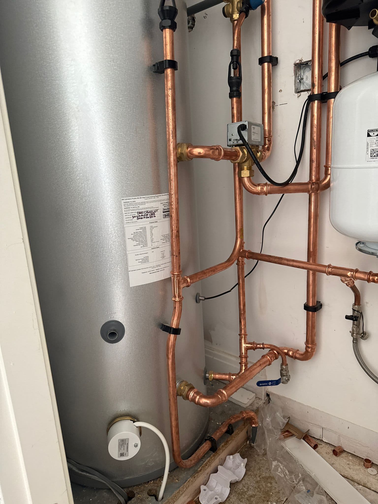 Newly installed unvented hot water cylinder with tidy soldered copper pipework and expansion vessel