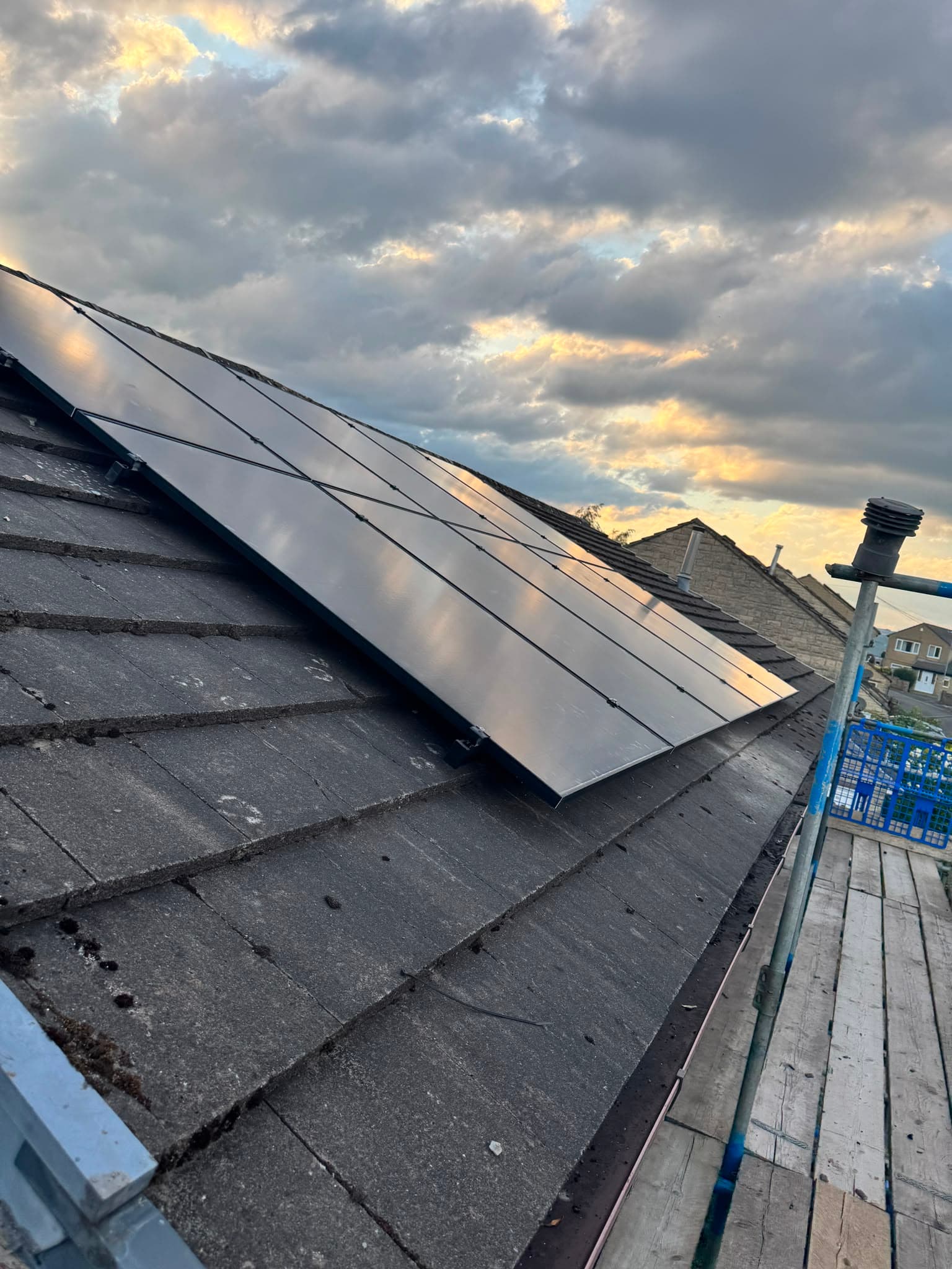 Completed eight-panel all-black solar PV array on a pitched tiled roof at sunset