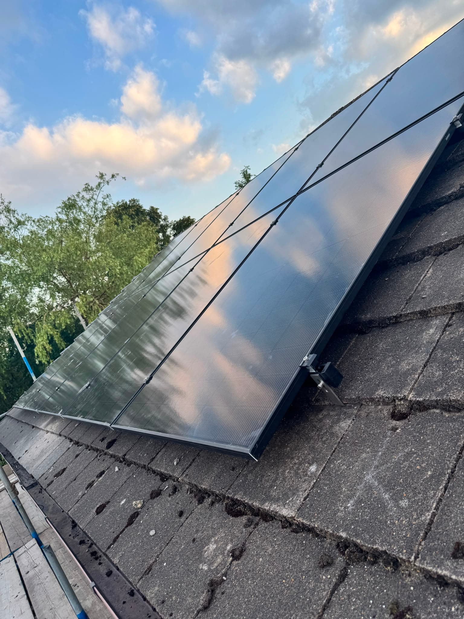 Close-up of all-black solar panels with mounting brackets on a tiled roof
