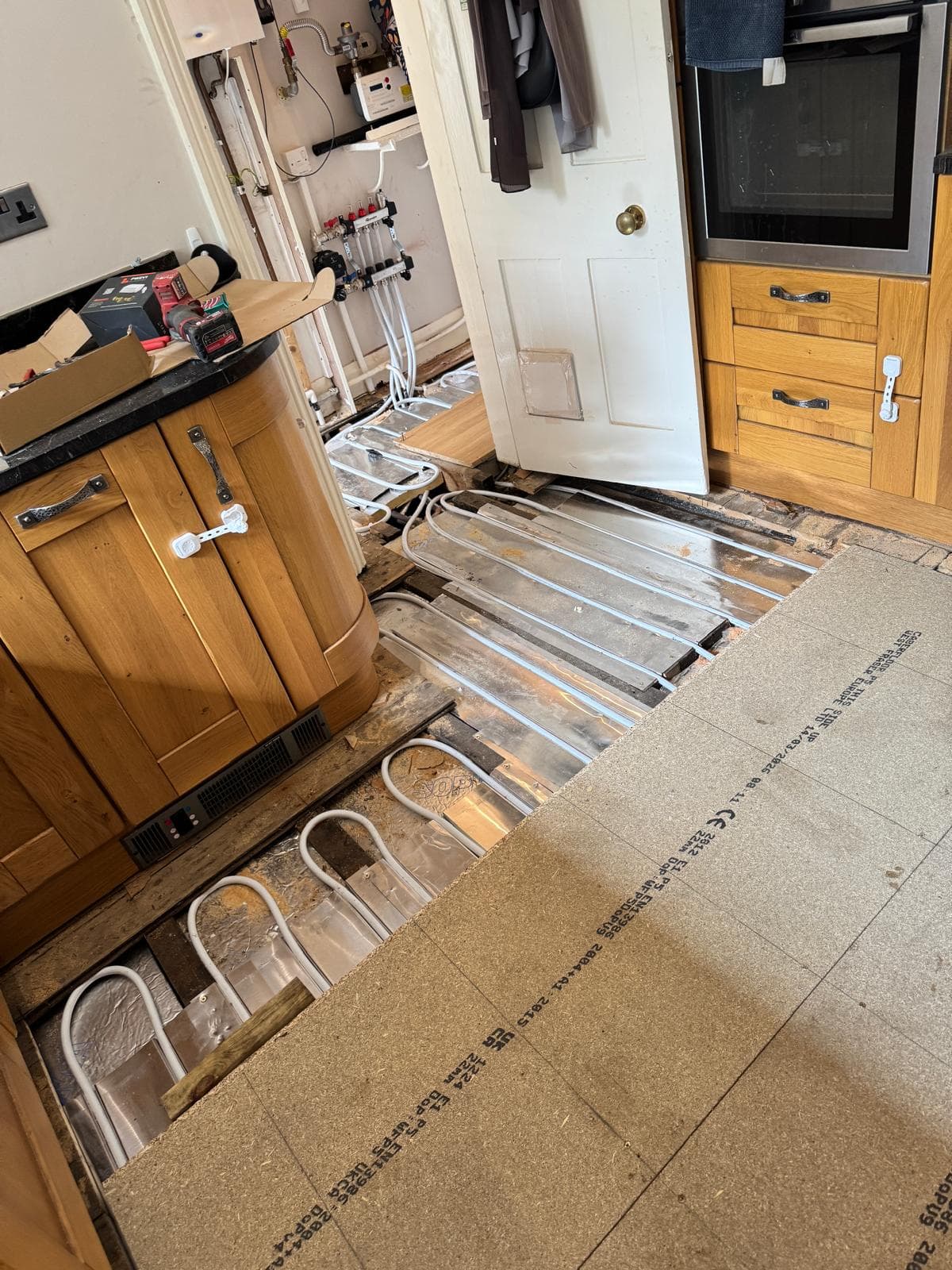 Kitchen floor lifted with underfloor heating pipe in aluminium spreader plates between the joists