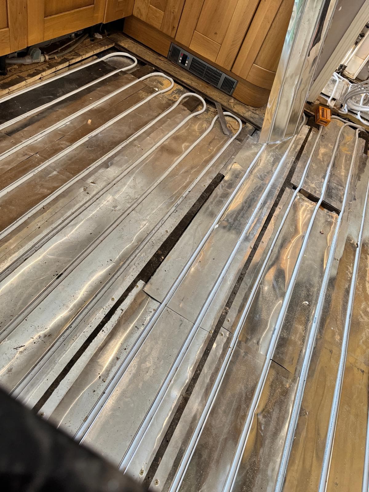 Underfloor heating pipe loops in spreader plates running beneath the kitchen units